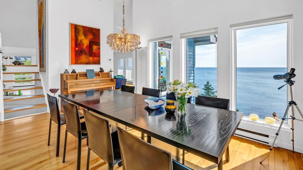 The dining room in the house with windows overlooking the water.