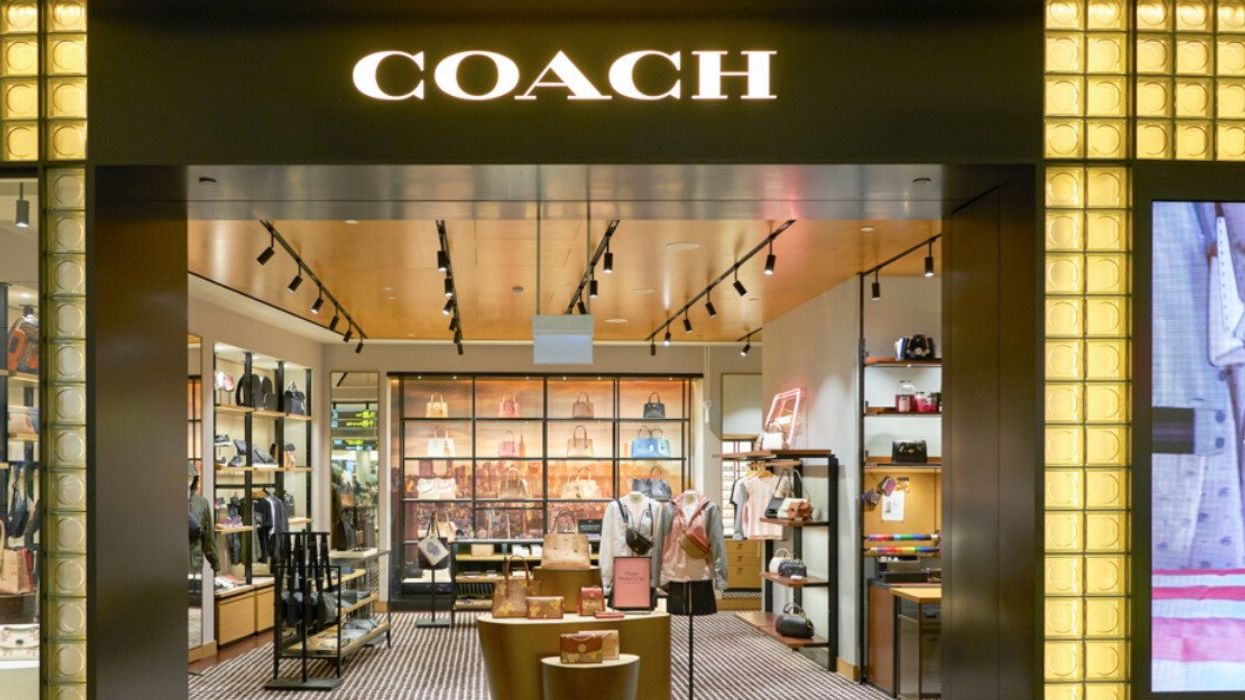 The exterior of a Coach entrance showing purses inside the store.