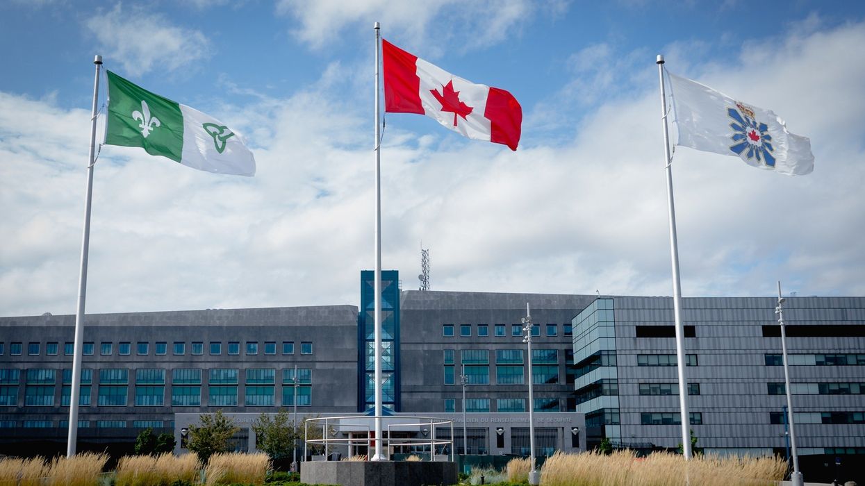 The exterior of a CSIS building in Canada, with the Canadian and CSIS flags flying outside of it.