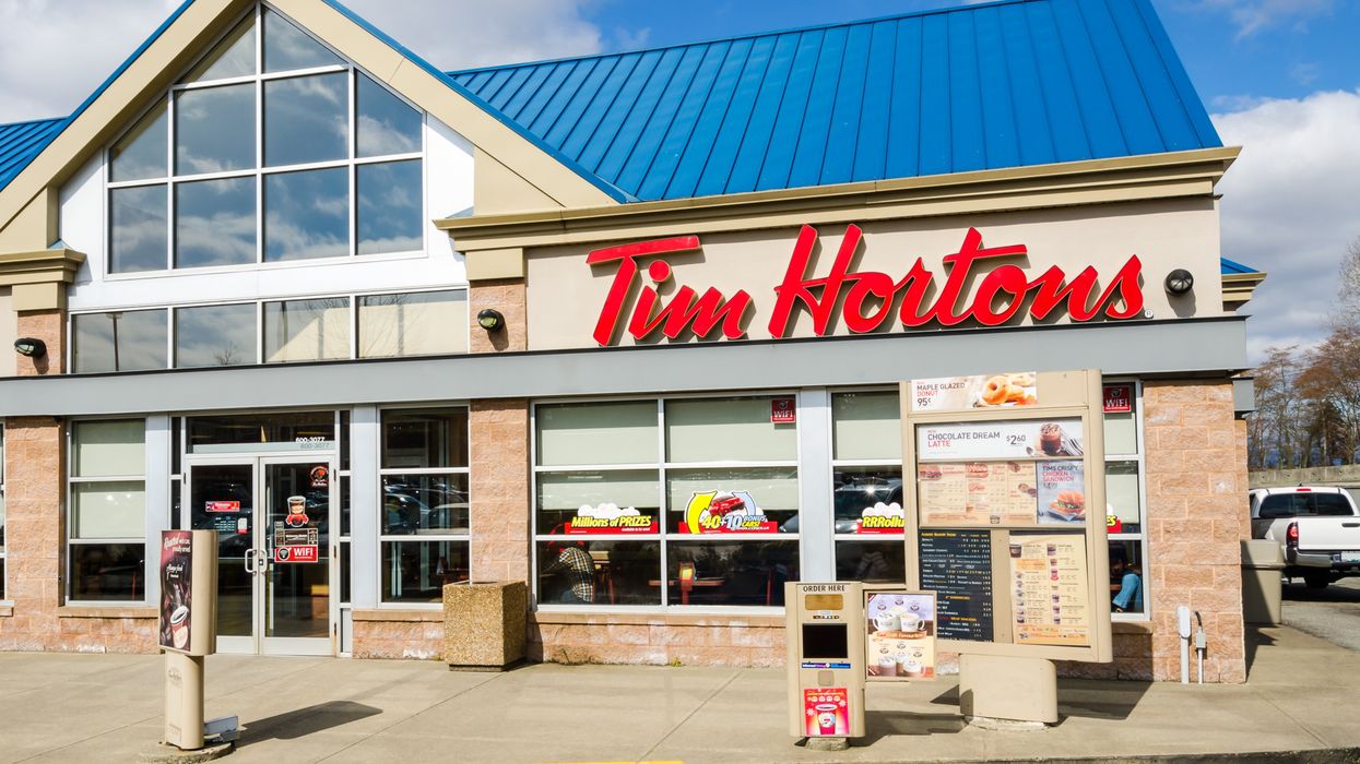 The exterior of a Tim Hortons building with a brown menu board.