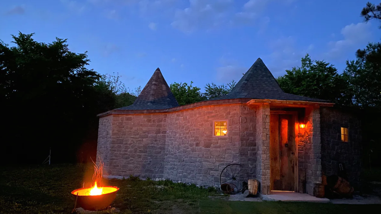 The exterior of the Gamekeeper Hut with a lit fire.