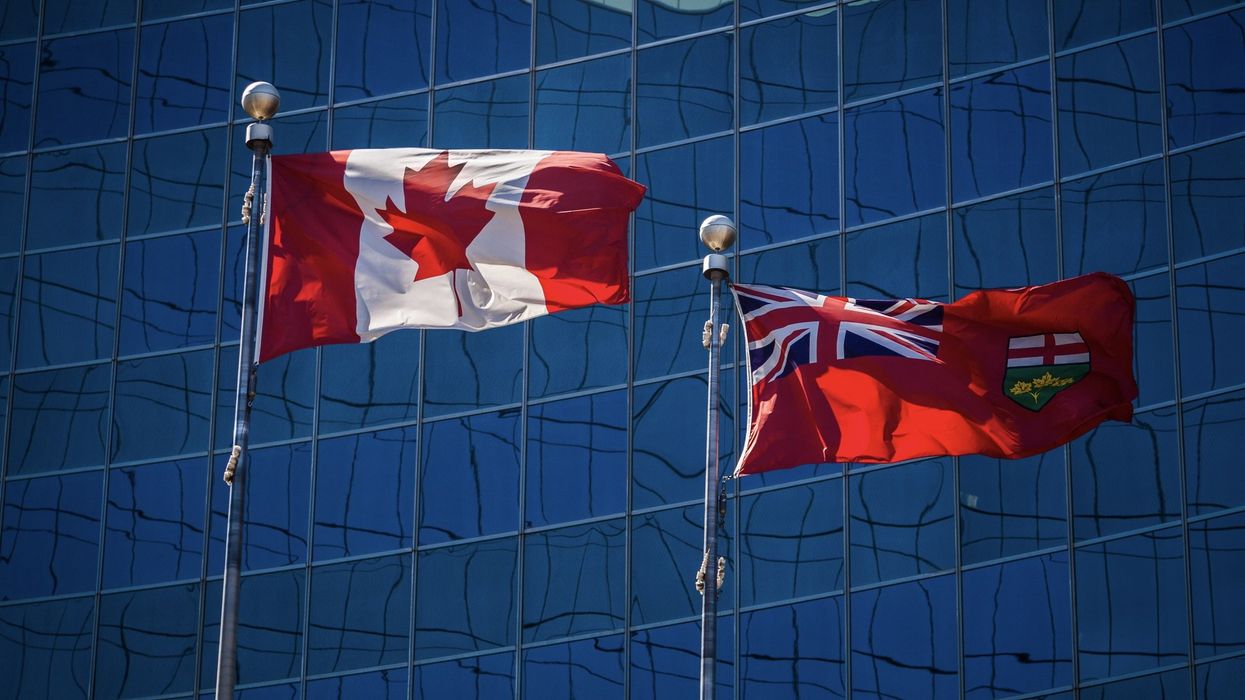 The fags of Canada and Ontario in front of a glass building.
