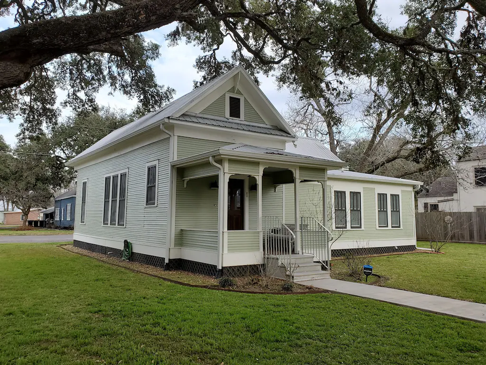 The front exterior and yard of a Victorian home in La Grange, TX.