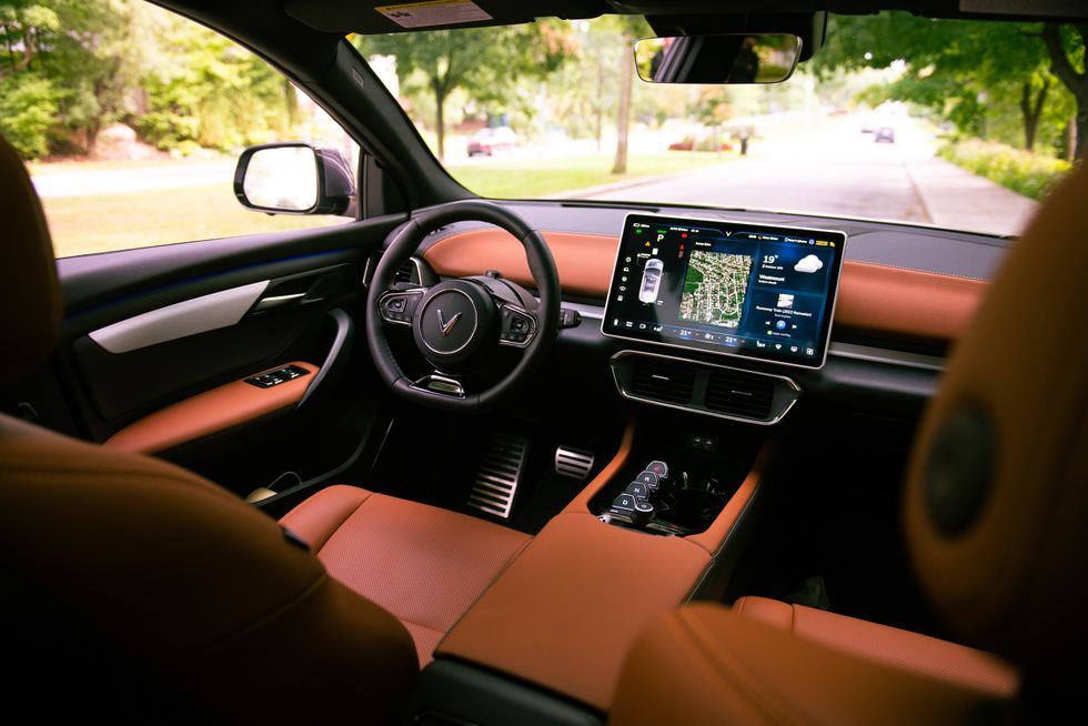 The front seats of a VinFast VF 8 as seen from the rear, showing the vegan leather trim, large screen display and black interior.