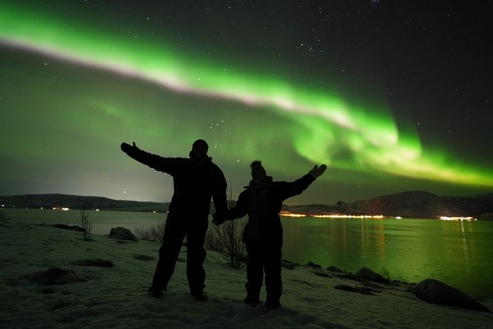 The northern lights with the silhouette of two people.