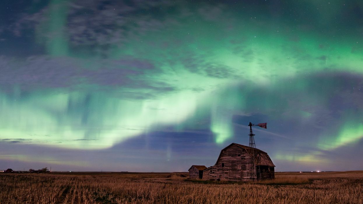 The nothern lights are seen in the sky over a barn in a field in Saskatchewan.