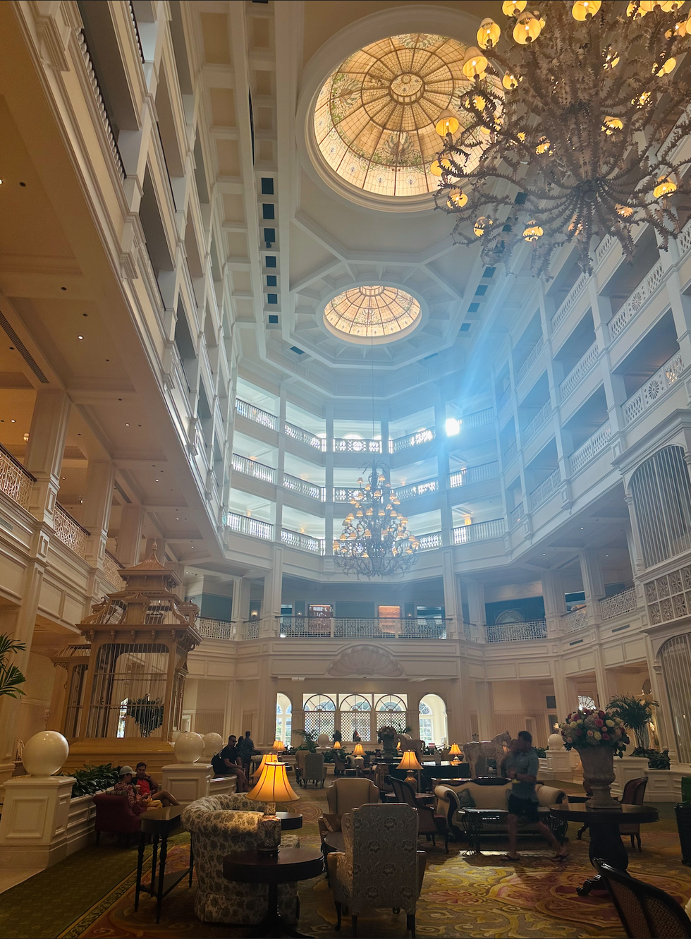 The opulent lobby of Disney\u2019s Grand Floridian Resort, featuring grand chandeliers, stained glass ceilings, and elegant seating areas.