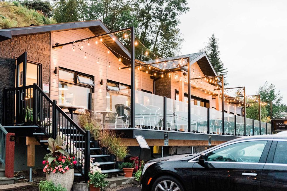 The outdoor patio of Le SAINTI at dusk, decorated with bright patio string lights.