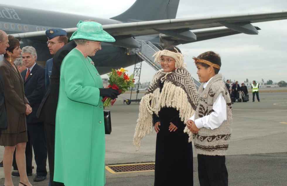 The queen is presented with flowers from two children.