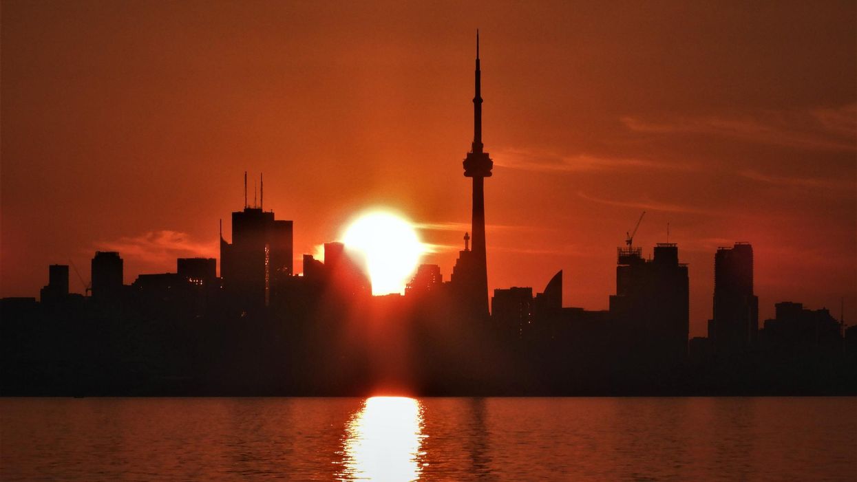 The sun rising behind the Toronto skyline.