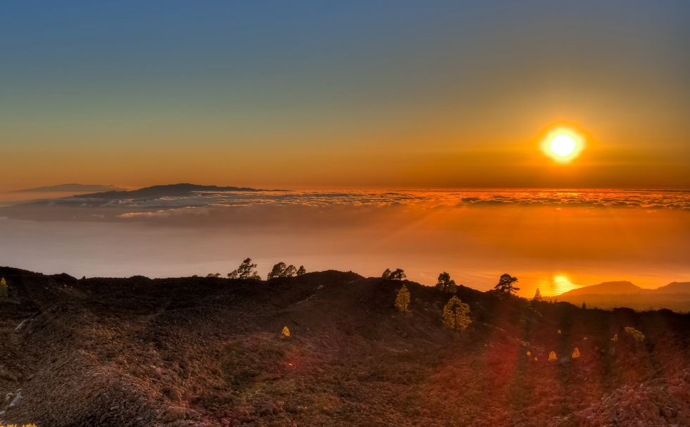 The sun sets over a sea of clouds as seen from the top of Mount Teide.