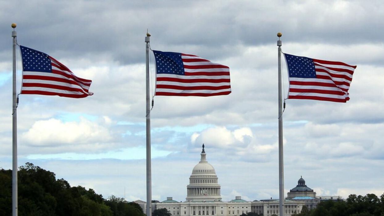 The United States Capitol behind U.S. flags in Washington, DC.