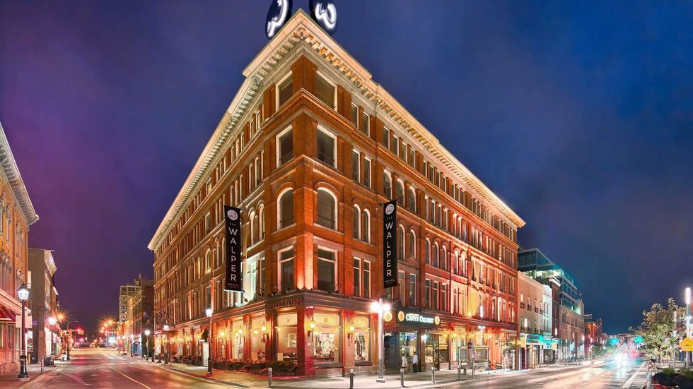 The Walper Hotel glows with warm exterior lights at a downtown street intersection at night.