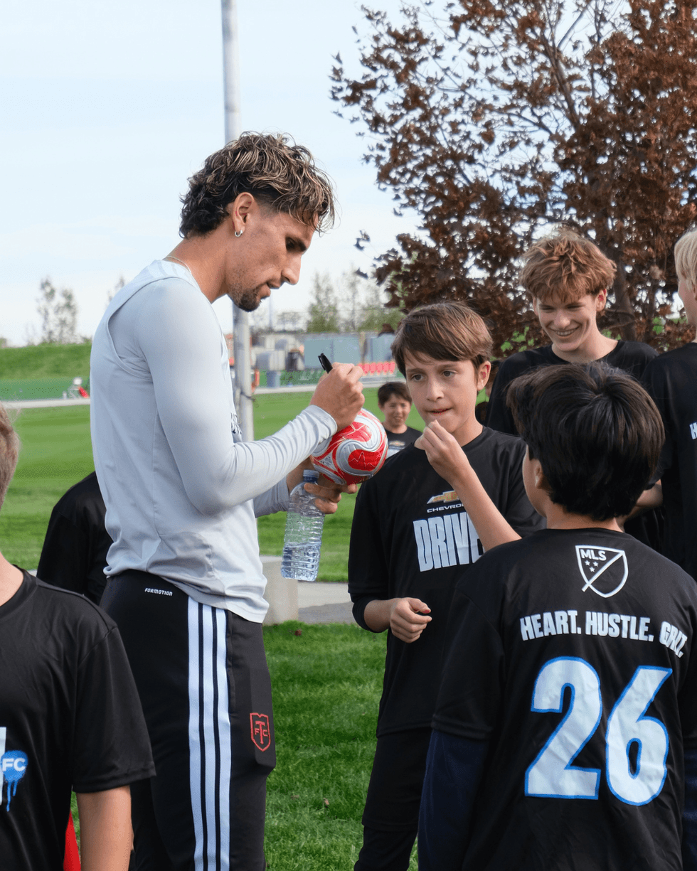 Theo Corbeanu signs a soccer ball for a Driven FC participant.