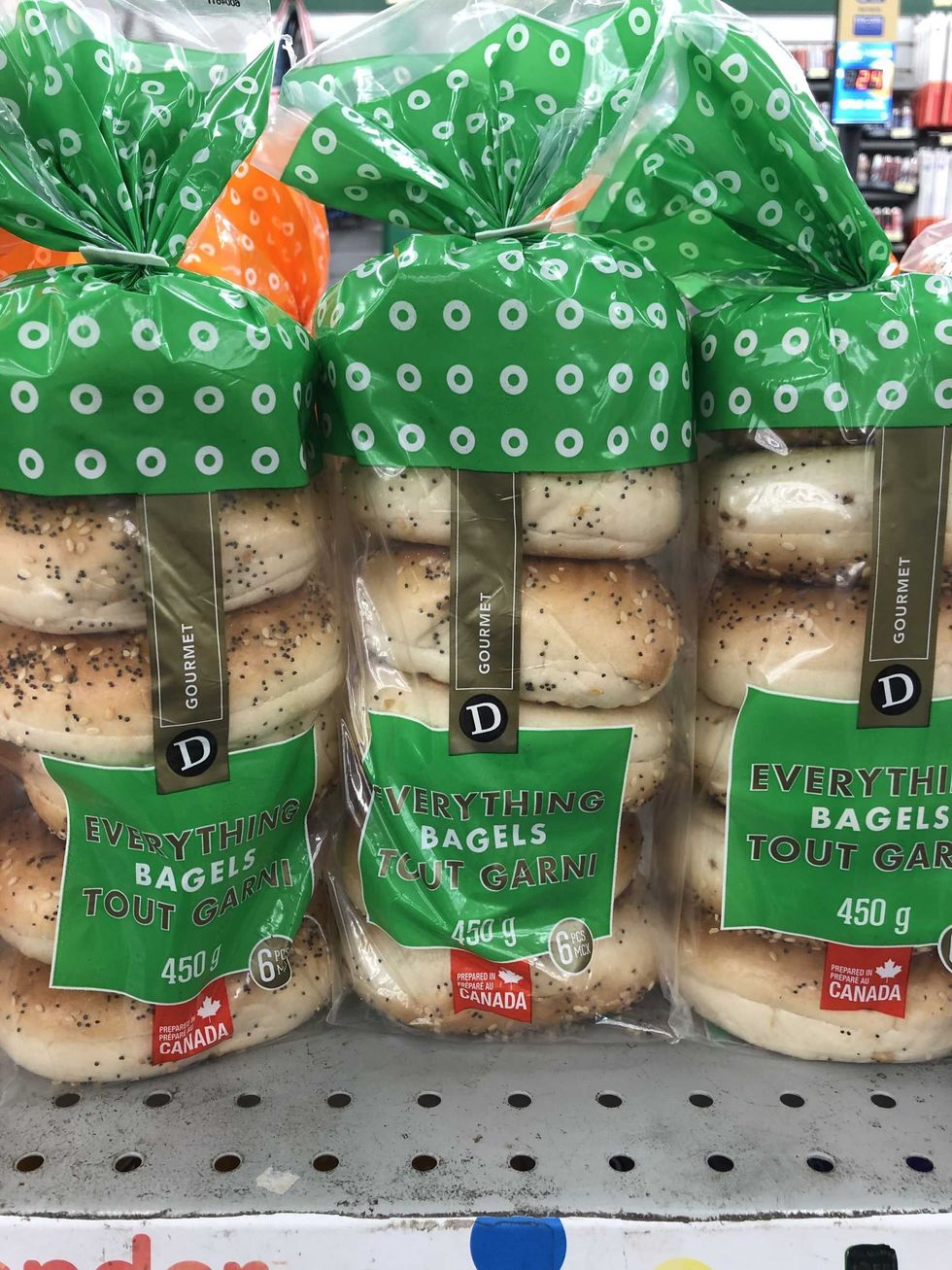 Three bags with bagels inside and a green and black label that says everything bagels.