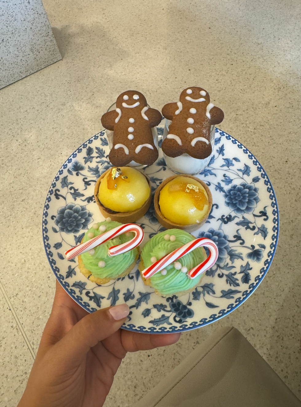 Three different kinds of desserts on a plate, one with a gingerbread cookie, another with gold and last with candy cane.