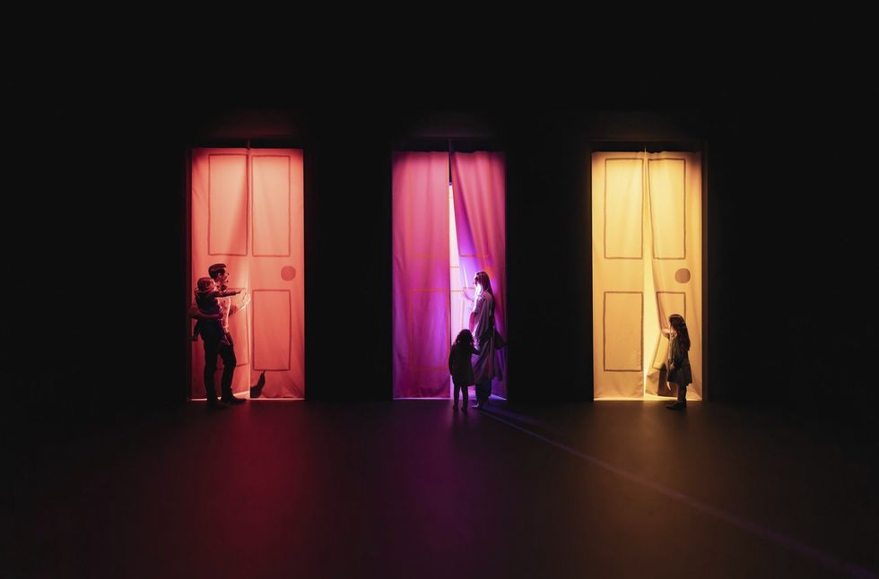 Three fabric-covered doorways in a row in a dark room, each with a curious person looking through.