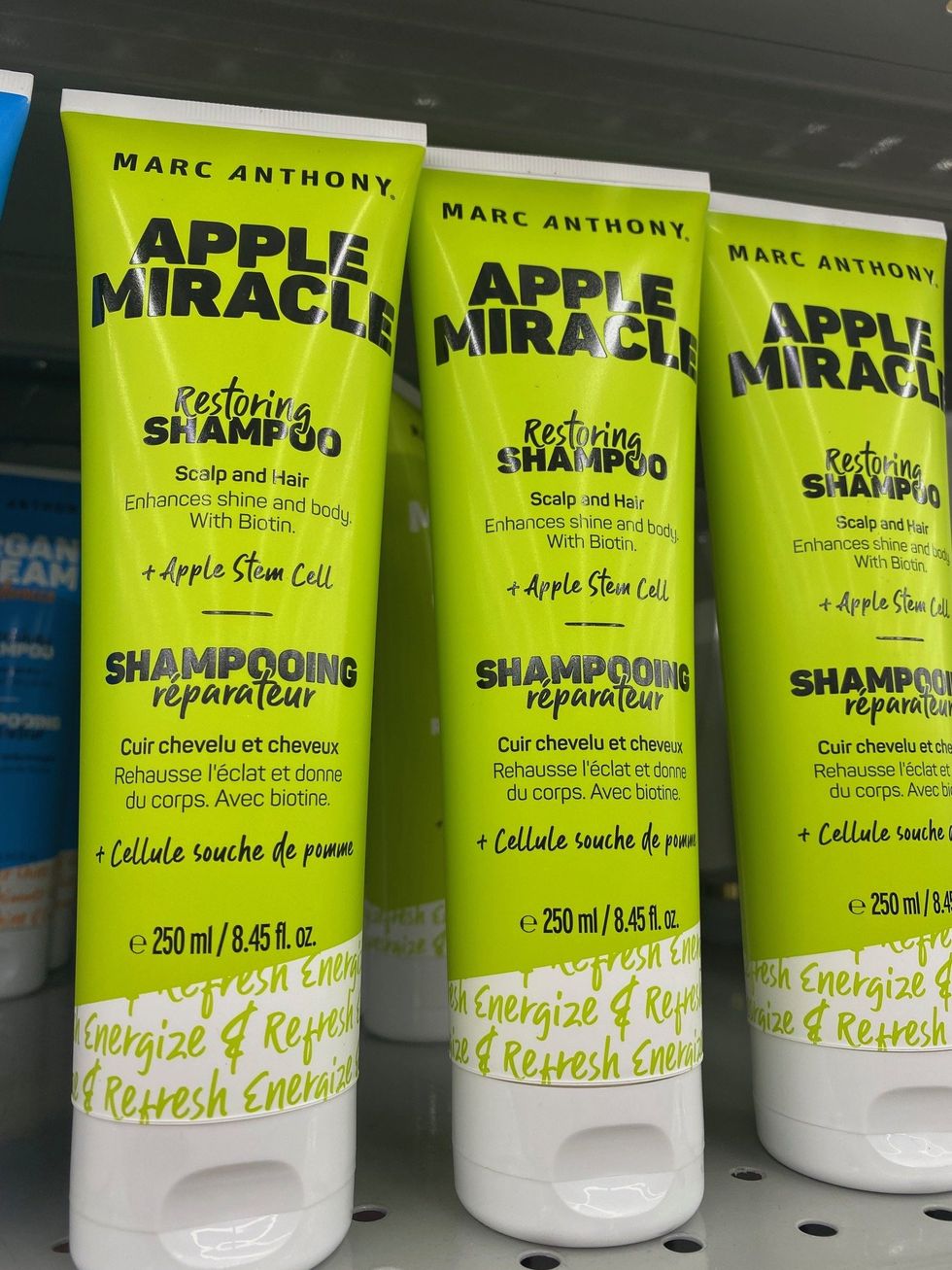 Three green bottles of shampoo on a store shelf.