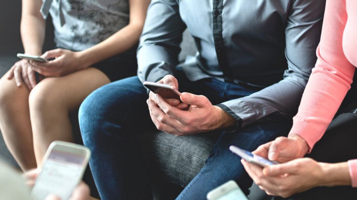 Three people sitting and looking at their phones.