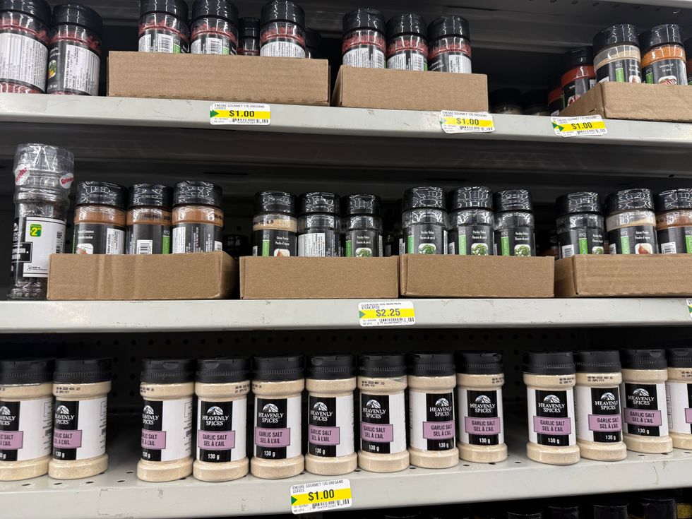 Three store shelves with many spices on them.