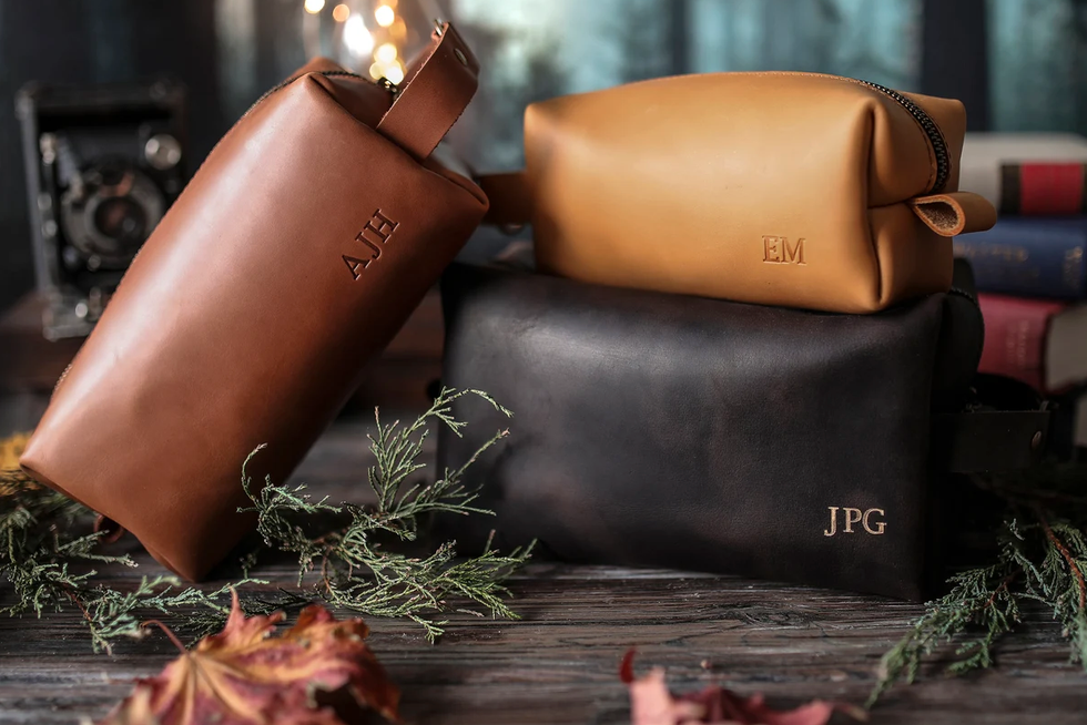 Three toiletry bags in brown, black and yellow.