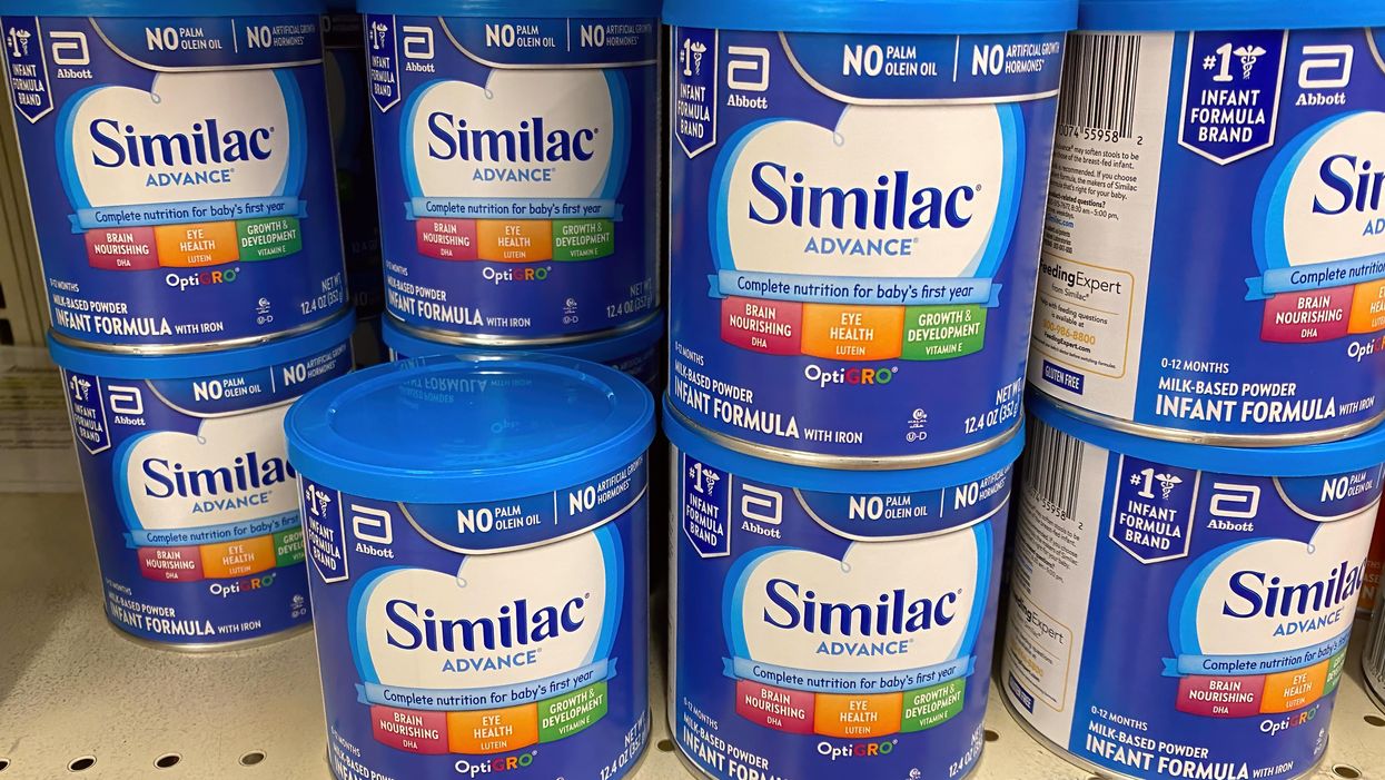 Tins of Similac baby formula on a shelf.