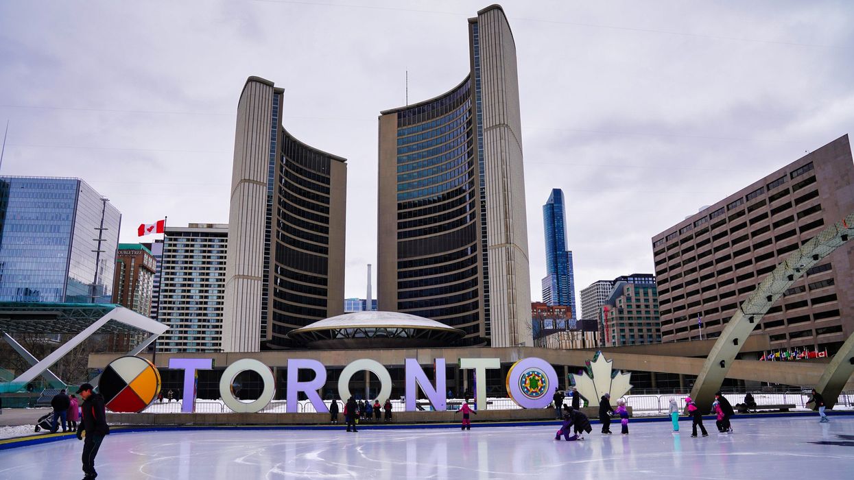 toronto city hall behind a toronto sign and skating rink