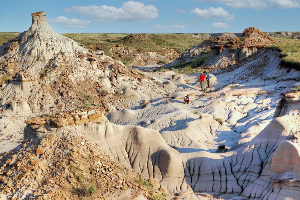 Tourists walk through rocky terrain in Dinosaur Provincial Park, Alberta.