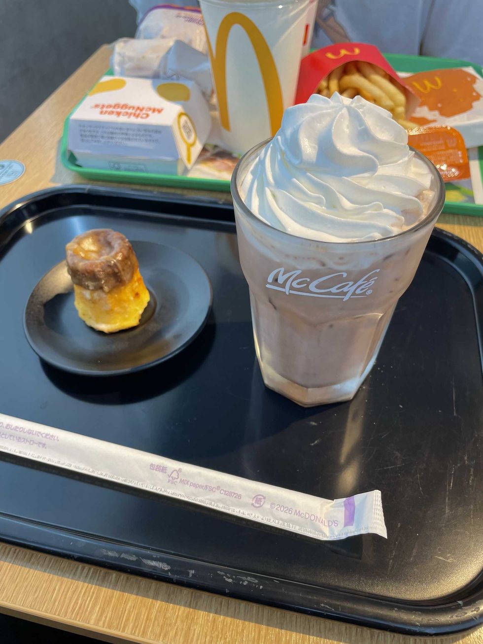 Tray with an Iced Chocolate with whipped cream and a Pudding Cake from McDonald's, with fries, chicken nuggets, and a soda in the background.
