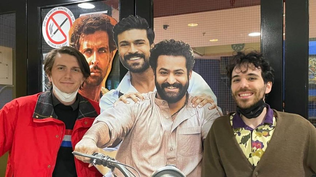 Tristan and a friend pose with an RRR standee.