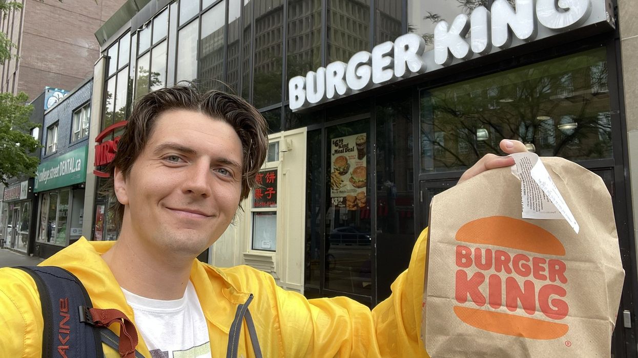 Tristan holding a Burger King bag in front of Burger King.