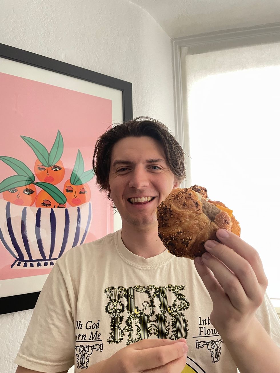 Tristan holding the Everything Croissant Breakfast Sandwich.