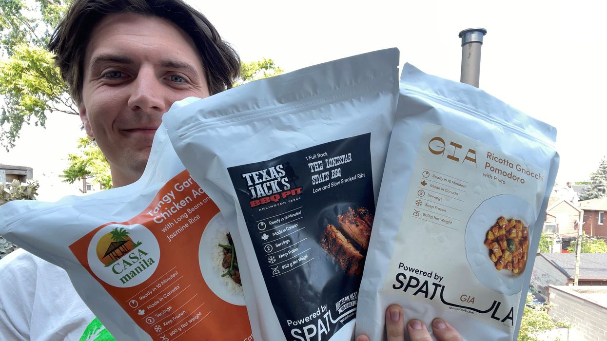 Tristan holding three of the frozen meal kits.