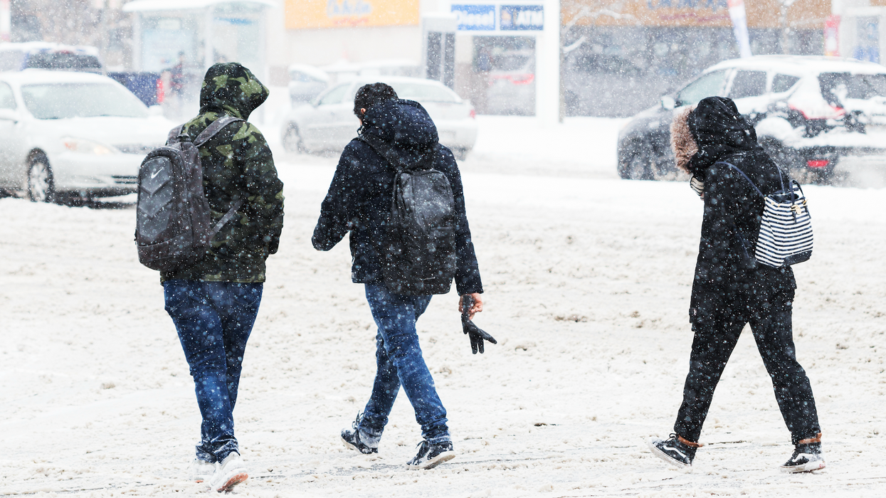 Trois personnes marchent dans une rue enneigée.