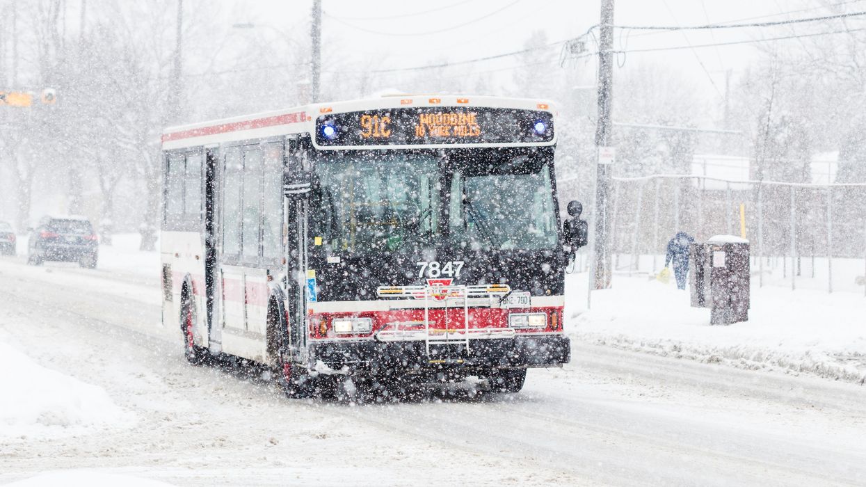 TTC bus drives along a snow covered suburban street during a winter snowstorm in Toronto.