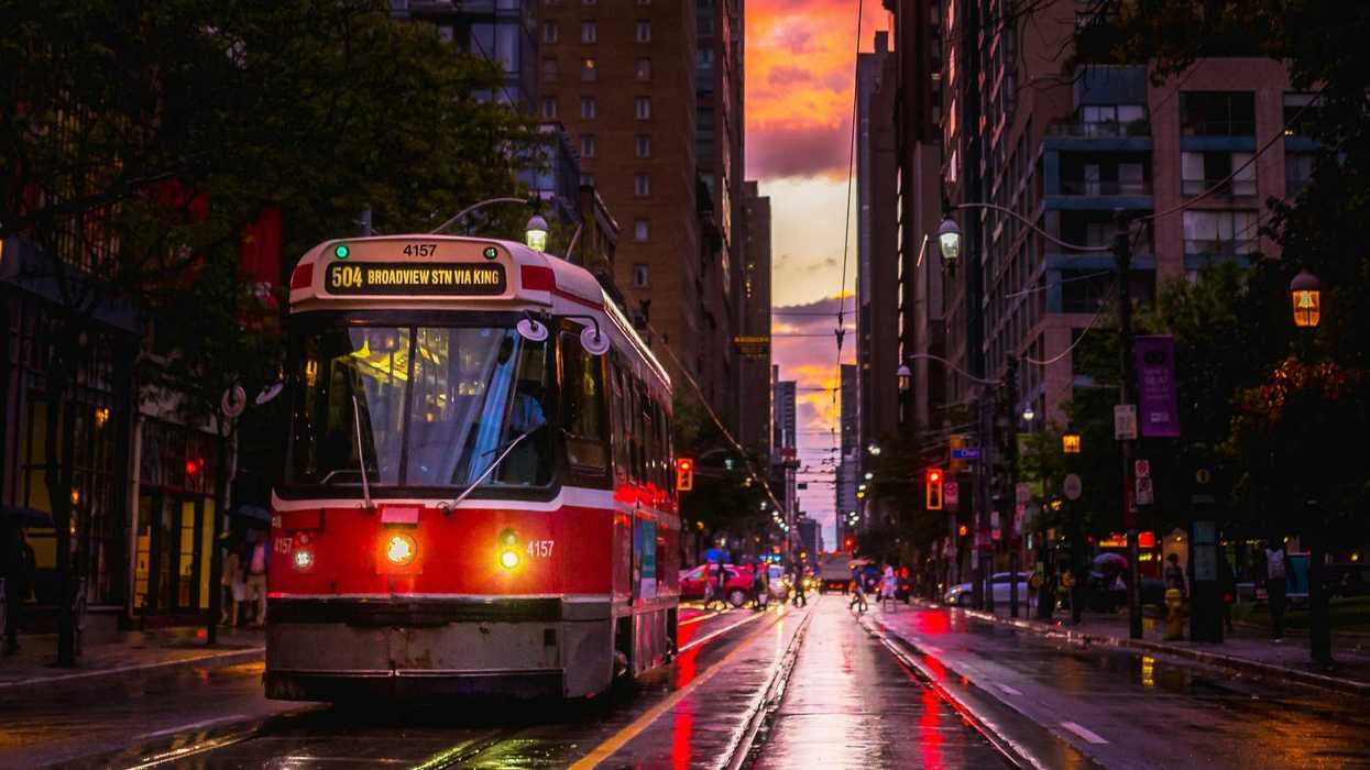 ttc streetcar and people crossing street in toronto at sunset after rainfall