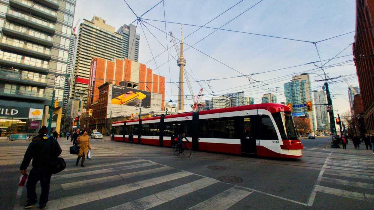 ttc streetcar going through an intersection in toronto with cn tower in the background