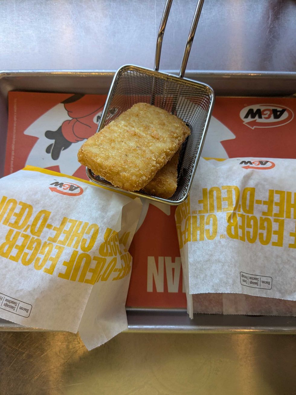 Two bacon-and-eggers in bags and two hashbrowns from A&W on a tray