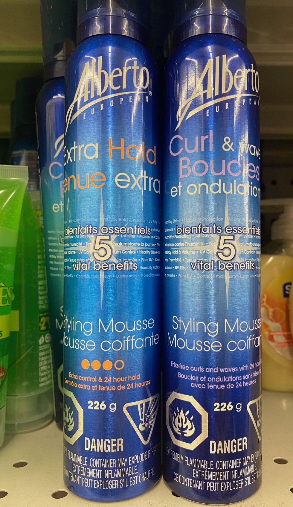 Two blue bottles of hair mousse on a store shelf.