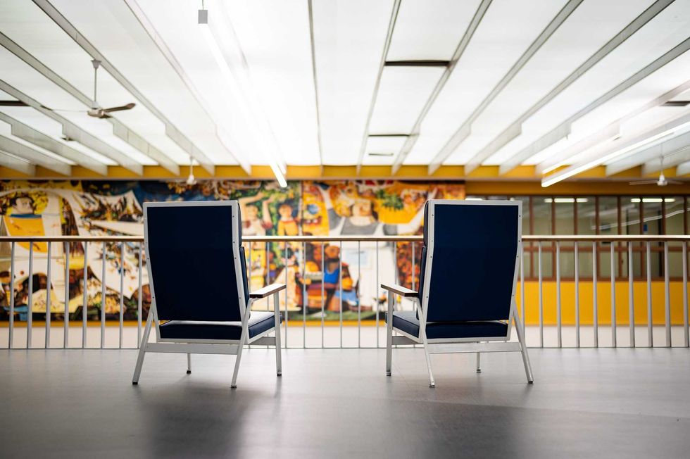Two blue chairs face a large panoramic mural.