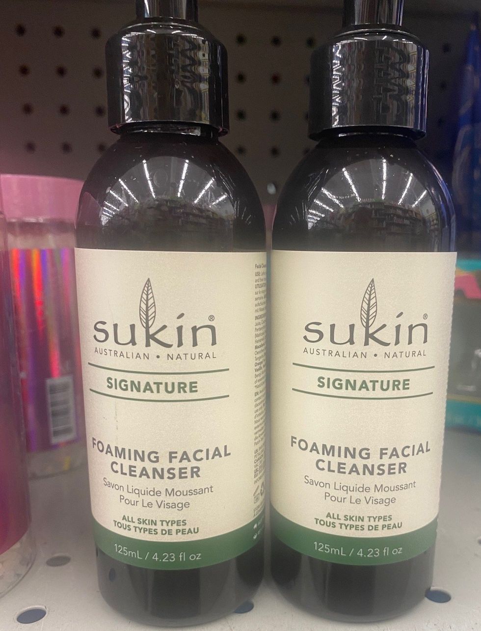 Two bottles of facial cleanser on a store shelf.