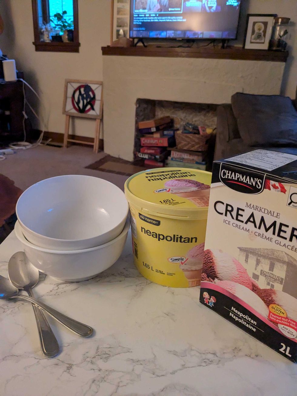 Two bowls and spoons on a table next to a tub of No Name and Chapman's ice cream