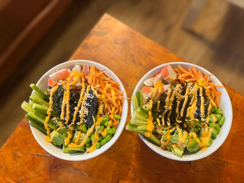 Two bowls containing rice, veggies, crab meat and sriracha mayo.