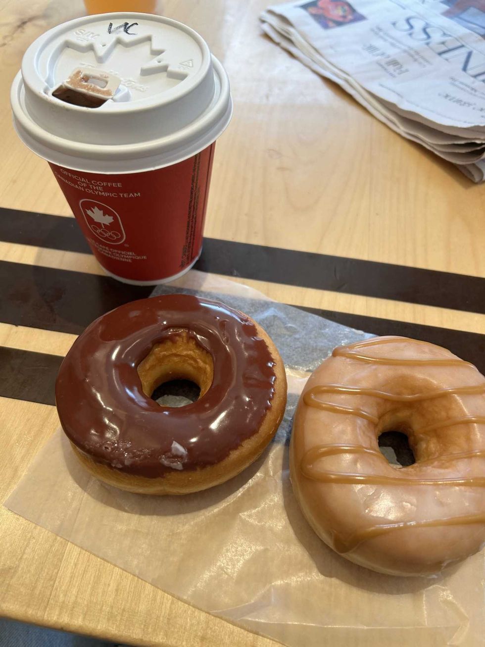 Two donuts next to a Time Hortons coffee cup.