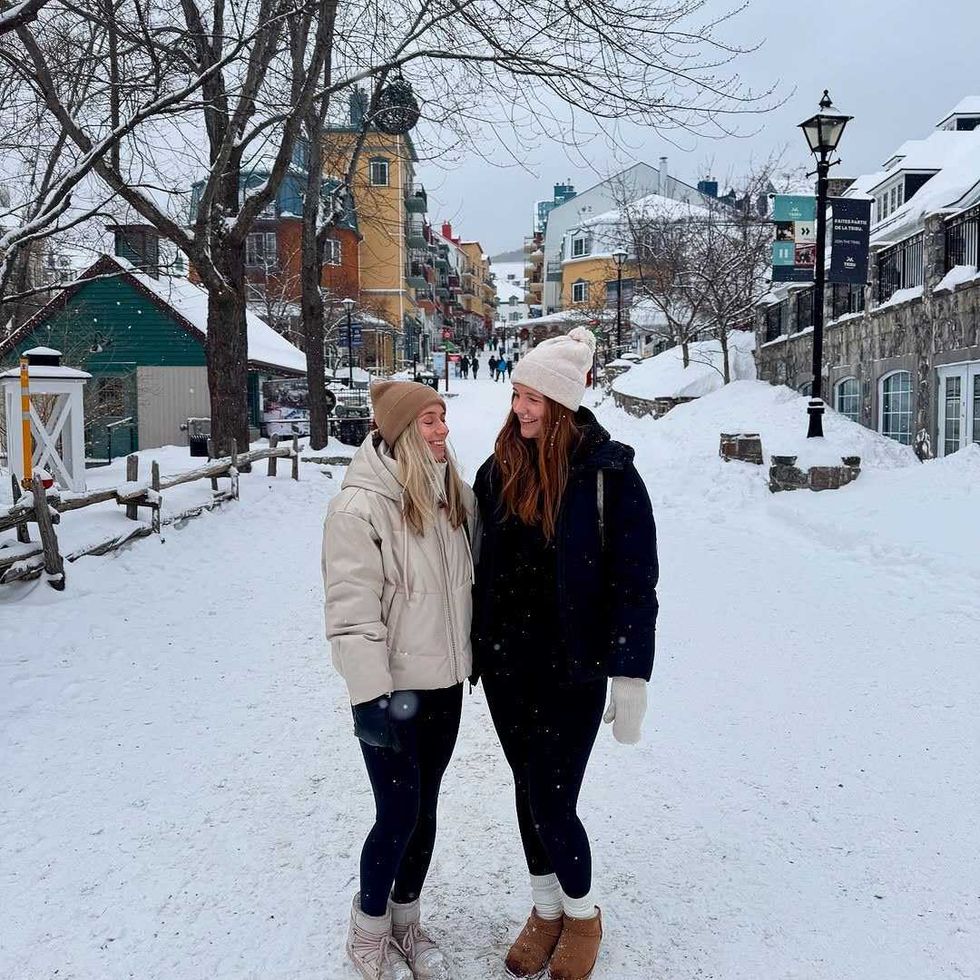Two friends smiling on a snowy street in Mont-Tremblant village.
