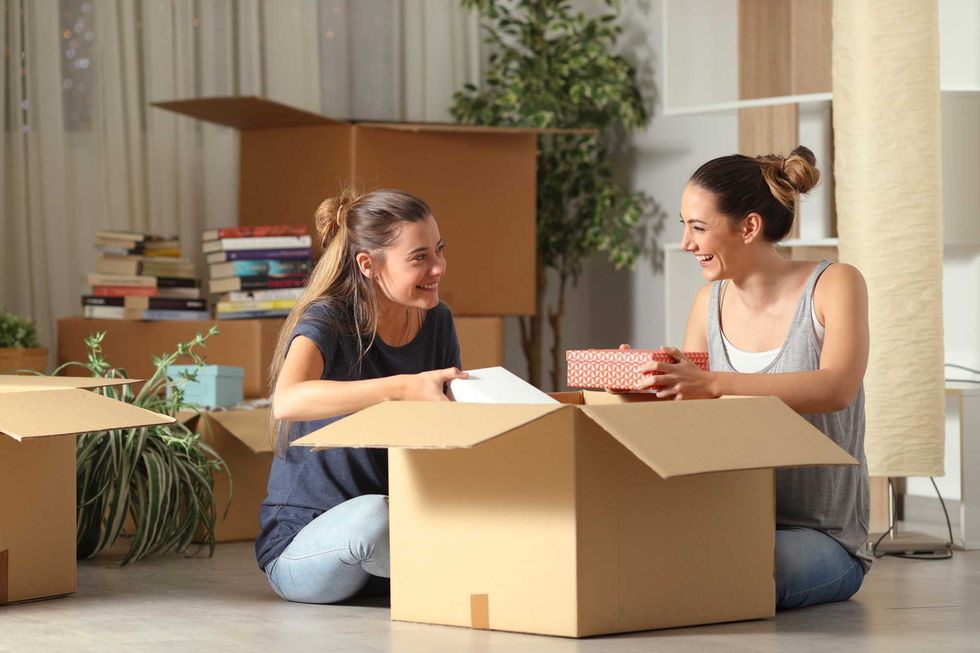 Two friends unpacking things from a cardboard box.