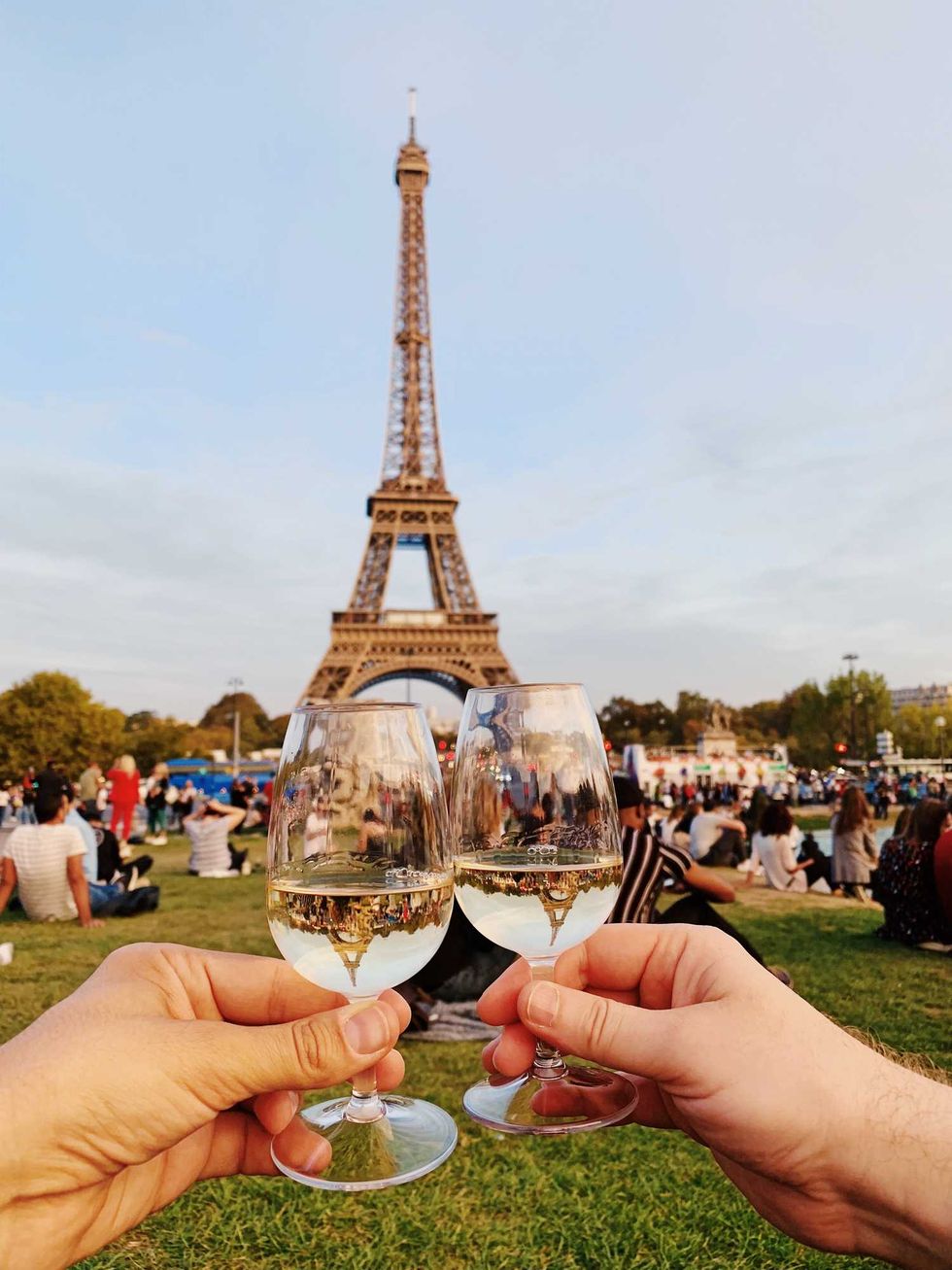 Two glasses touching in front of the Eiffel tower
