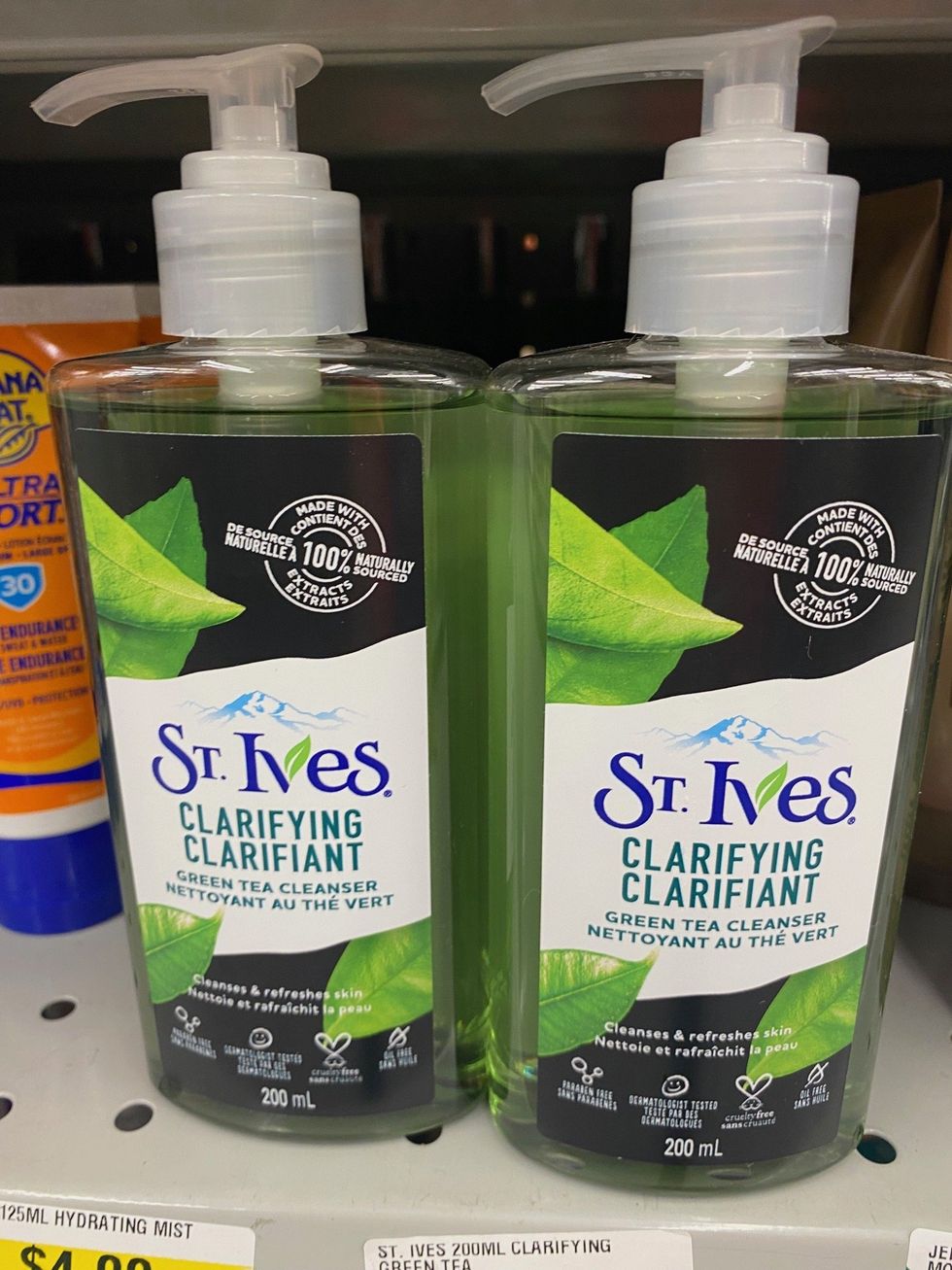 Two green and black coloured bottles of face wash on a store shelf.