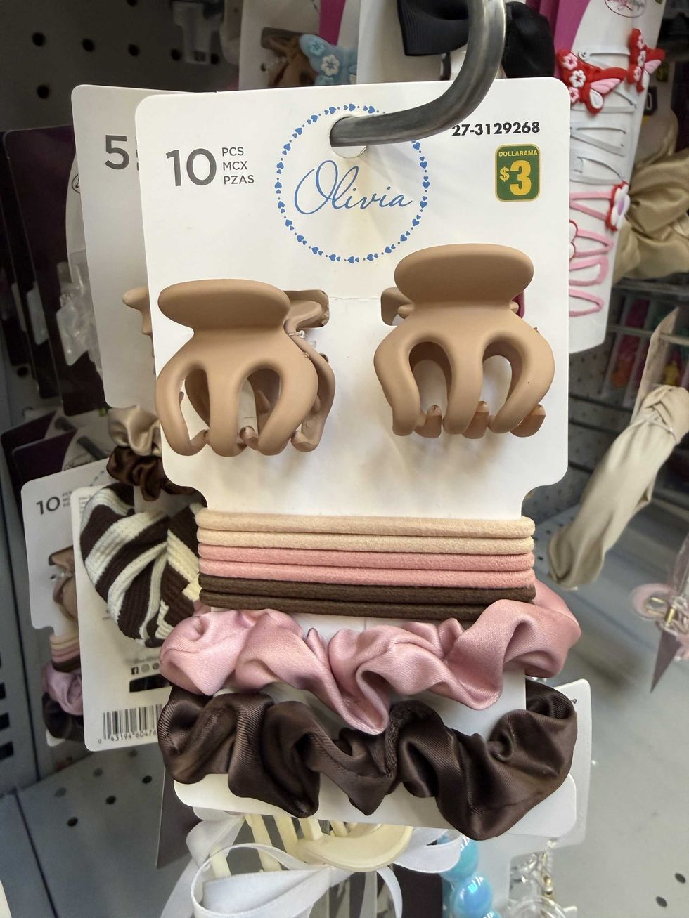 Two hair clips and several beige, pink and brown hair ties hanging on a store shelf.