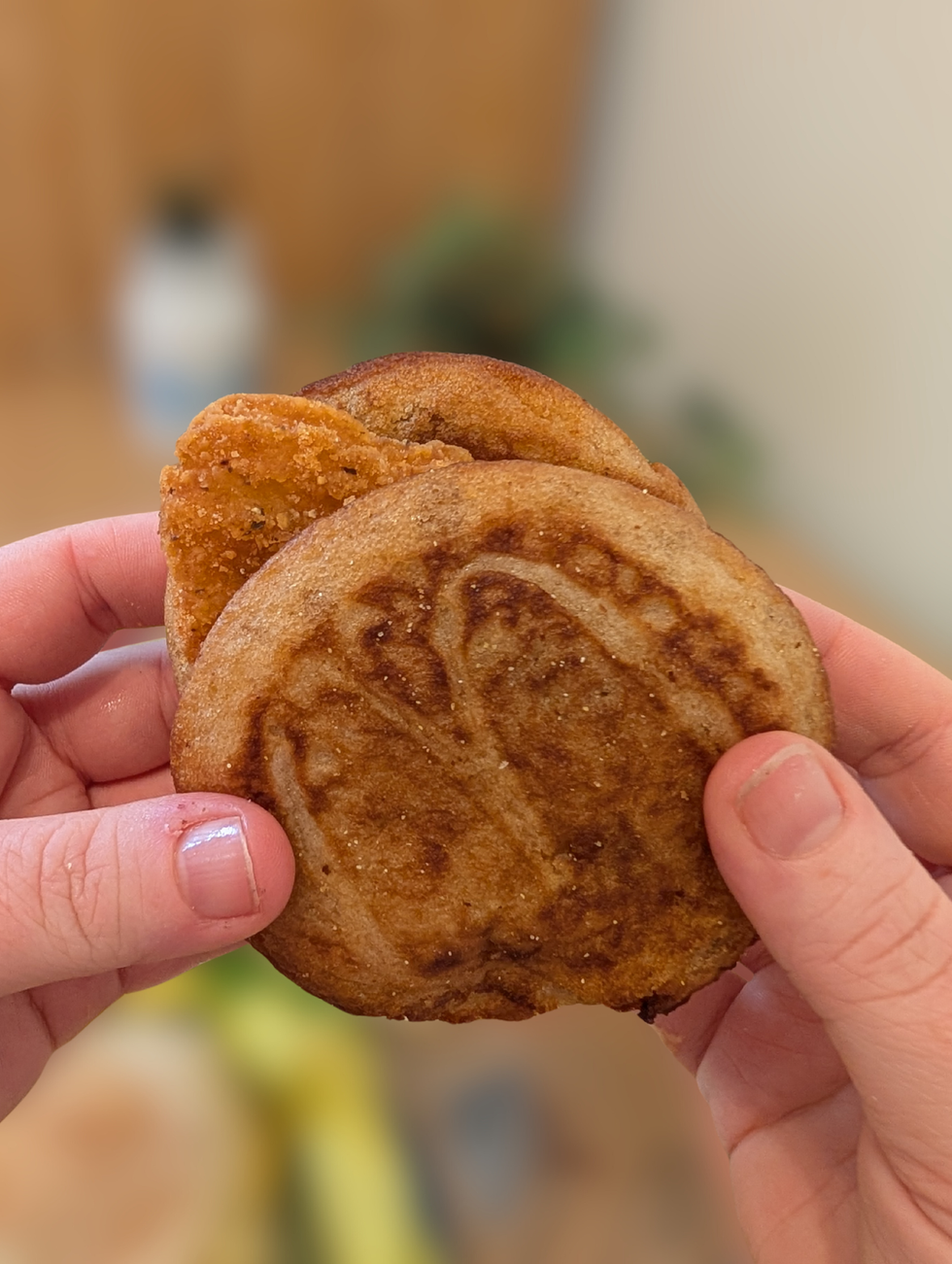 Two hands holding a Chicken McGriddles. 